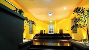 Un pasillo bien iluminado con paredes amarillas, una escalera y plantas decorativas.