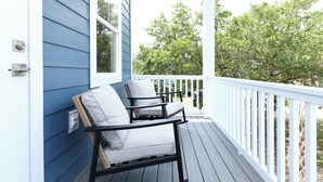 A porch with two rocking chairs, a white railing, and a view of trees. - 5 BR Beach House with a Private Pool! Grace's Places "FKA Blessed in Waves" (Surfside Beach)