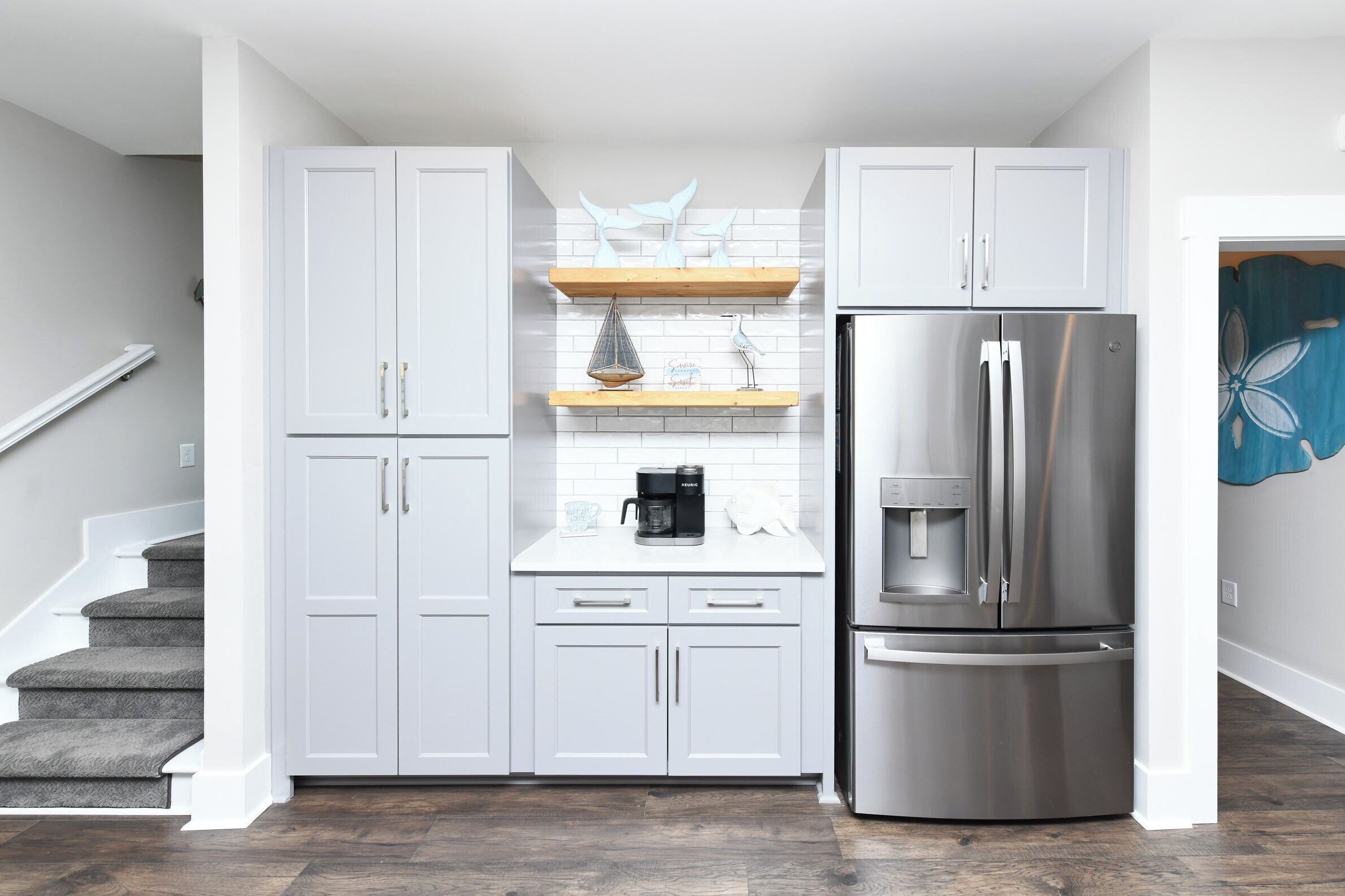 A modern kitchen with white cabinets, a stainless steel refrigerator, and a coffee maker on the countertop.