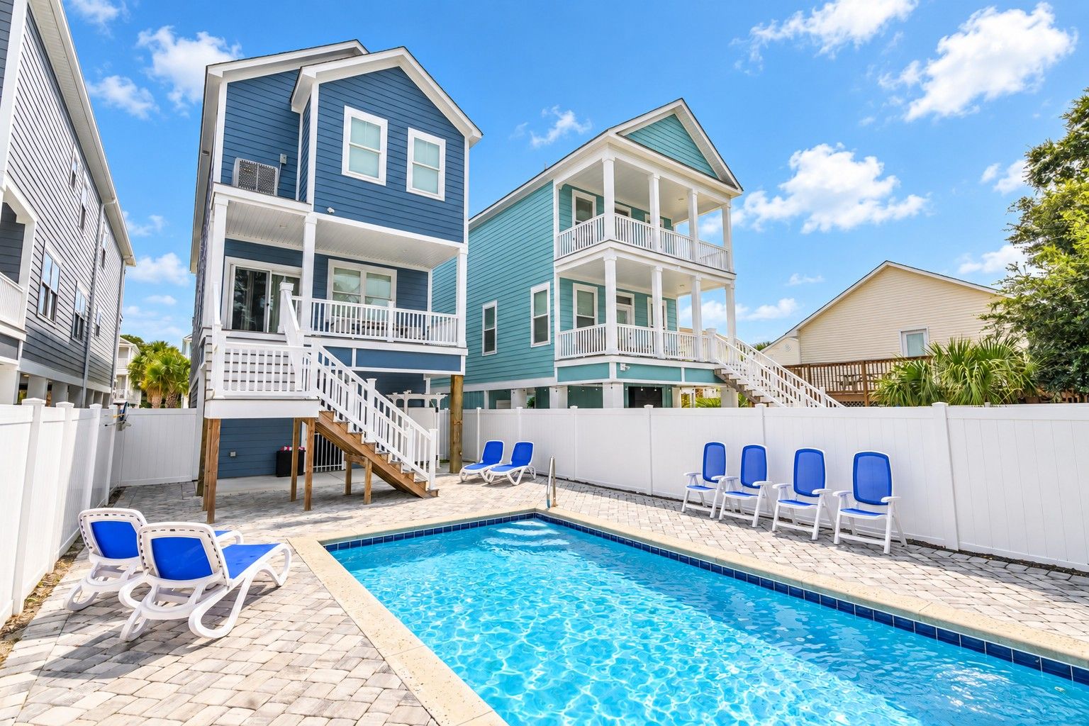 A swimming pool with lounge chairs, a staircase, and a two-story building with balconies.