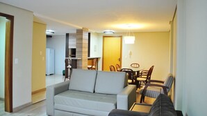 Una sala de estar con un sofá, una mesa de comedor con sillas y una zona de cocina al fondo.