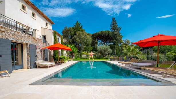 A swimming pool with lounge chairs and umbrellas, surrounded by a stone wall and trees. - Nice villa completely renovated (Gassin)