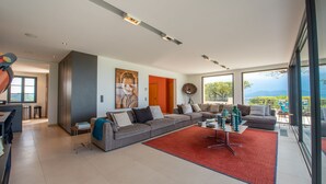 A modern living room with a large grey sectional sofa, a red rug, and a dining area with a table and chairs. - Nice villa completely renovated (Gassin)