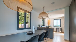 A modern kitchen with a large island, black chairs, and pendant lighting. - Nice villa completely renovated (Gassin)