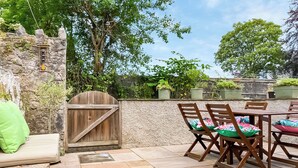 Eine Terrasse mit Steinbelag, Holzmöbeln und einer Steinmauer.