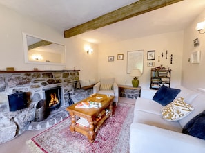 Una sala de estar acogedora con una chimenea de piedra, un sofá blanco, una mesa de centro de madera y una estantería.