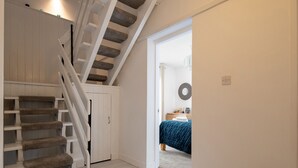 A staircase with white railings and stone steps, leading to a bedroom with a blue bedspread. - Rivage - Two Bedroom Cottage, Sleeps 4 (Deganwy)