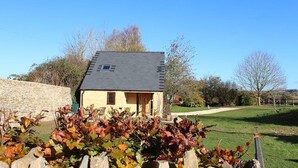 A two-story house with a sloped roof, a small window, and a door. - Amazing views in luxury cottage (Cheltenham)