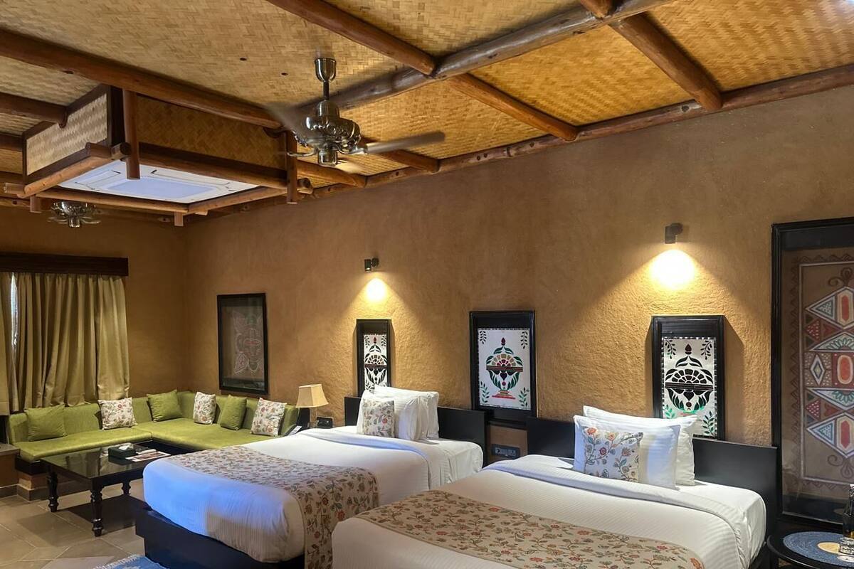 A hotel room with two beds, a sofa, a coffee table, and a ceiling fan.