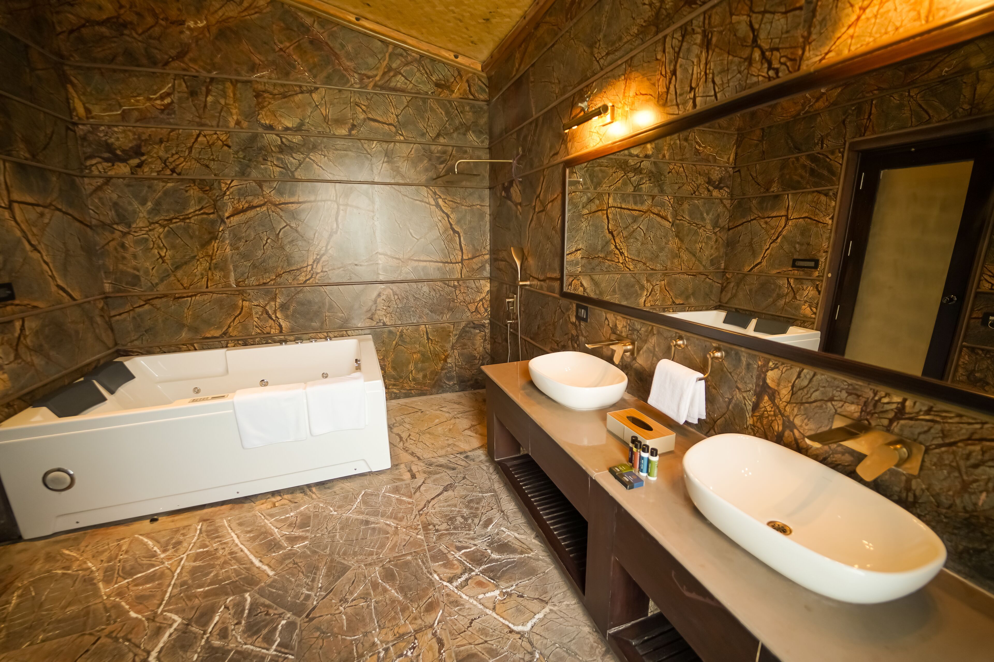 A bathroom with a marble floor, a large bathtub, two sinks, and a mirror above the sinks.