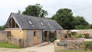 Een stenen cottage met een schuin dak, een houten deur en een bordje met de tekst 'Bury Fields Cottage'.
