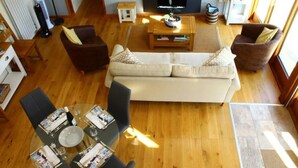 Een woonkamer met een bank, twee fauteuils, een salontafel en een televisie.
