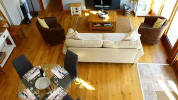 A living room with a sofa, two armchairs, a coffee table, and a TV.