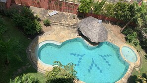 Ein Pool mit einem einzigartigen, herzförmigen Design, umgeben von einer Steindeck und üppiger Vegetation.