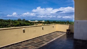 Eine Dachterrasse mit Blick auf das Meer und Palmen.
