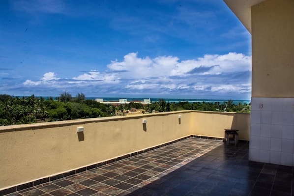 Una terraza en la azotea con vistas al océano y palmeras.