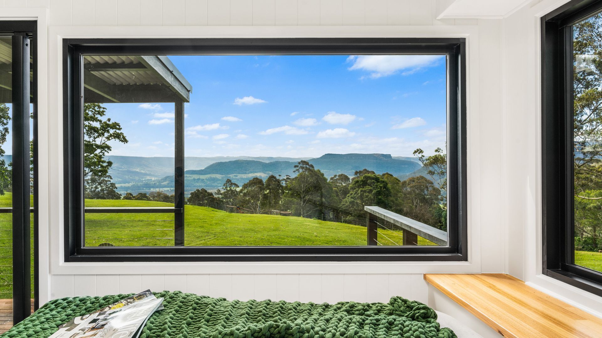 A room with a large window offering a view of a green landscape and distant hills.