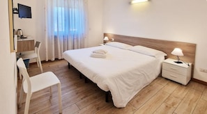 Une chambre d’hôtel comprenant un lit, des tables de chevet, un bureau, une chaise et un téléviseur.