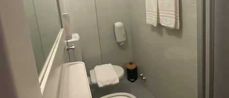 A bathroom with a bathtub, a toilet, a hand dryer, and a mirror.