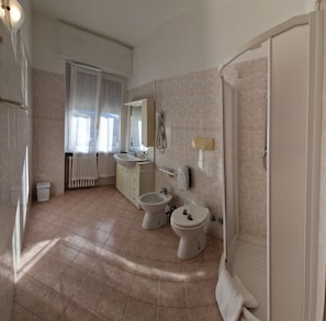 Une salle de bain comprenant des toilettes, un bidet, un lavabo et un miroir.