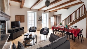 Amplia sala de estar con chimenea, televisor y comedor con mantel rojo.