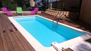 A rectangular swimming pool with a ladder, surrounded by wooden decking and three colorful lounge chairs. - T3 - First floor - With swimming pool - Rated 5 * furnished for tourism (Piana)