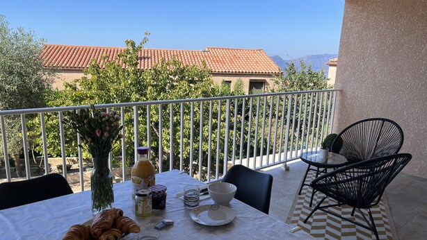A balcony with a table set for breakfast, including croissants, a vase with flowers, and a bottle of juice. - T3 - First floor - With swimming pool - Rated 5 * furnished for tourism (Piana)