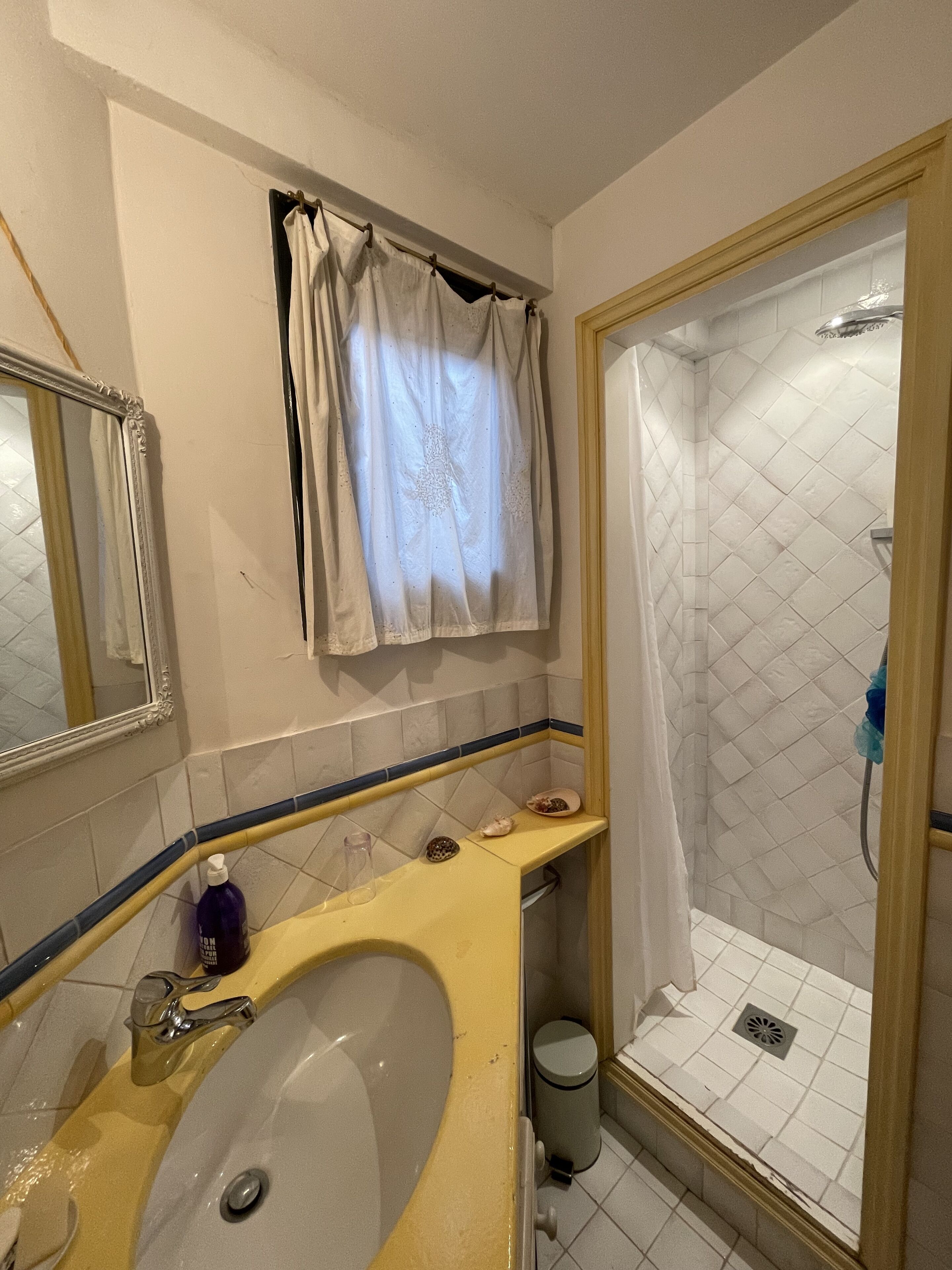 Un bagno con lavandino, specchio, doccia e porta asciugamani.