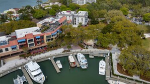 A marina with several boats docked, surrounded by buildings and greenery.