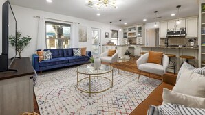 Ein modernes Wohnzimmer mit einem blauen Sofa, weißen Sessel und einem Couchtisch.