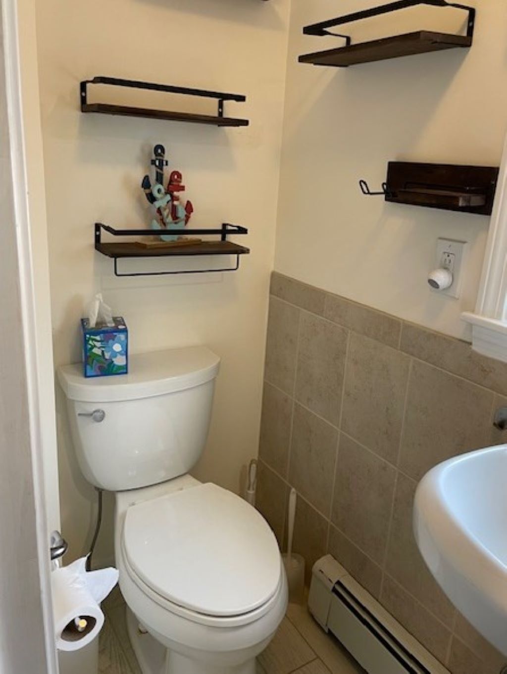 Un bagno piccolo con il water, uno scaffale con un oggetto decorativo e un porta asciugamani.