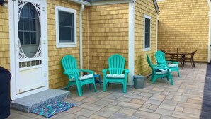 A house with a wooden exterior, a front porch with turquoise Adirondack chairs, a small table, and a rug. - 183 #3 N. Shore Blvd (Sandwich)