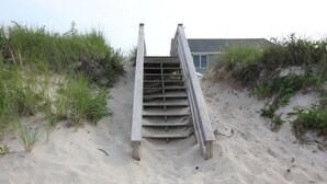 A wooden staircase leading up a sandy slope with a building in the background. - 183 #3 N. Shore Blvd (Sandwich)