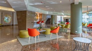 A spacious lobby with a marble floor, modern seating, and a staircase in the background. - Holiday Inn San Jose La Sabana by IHG (San José)