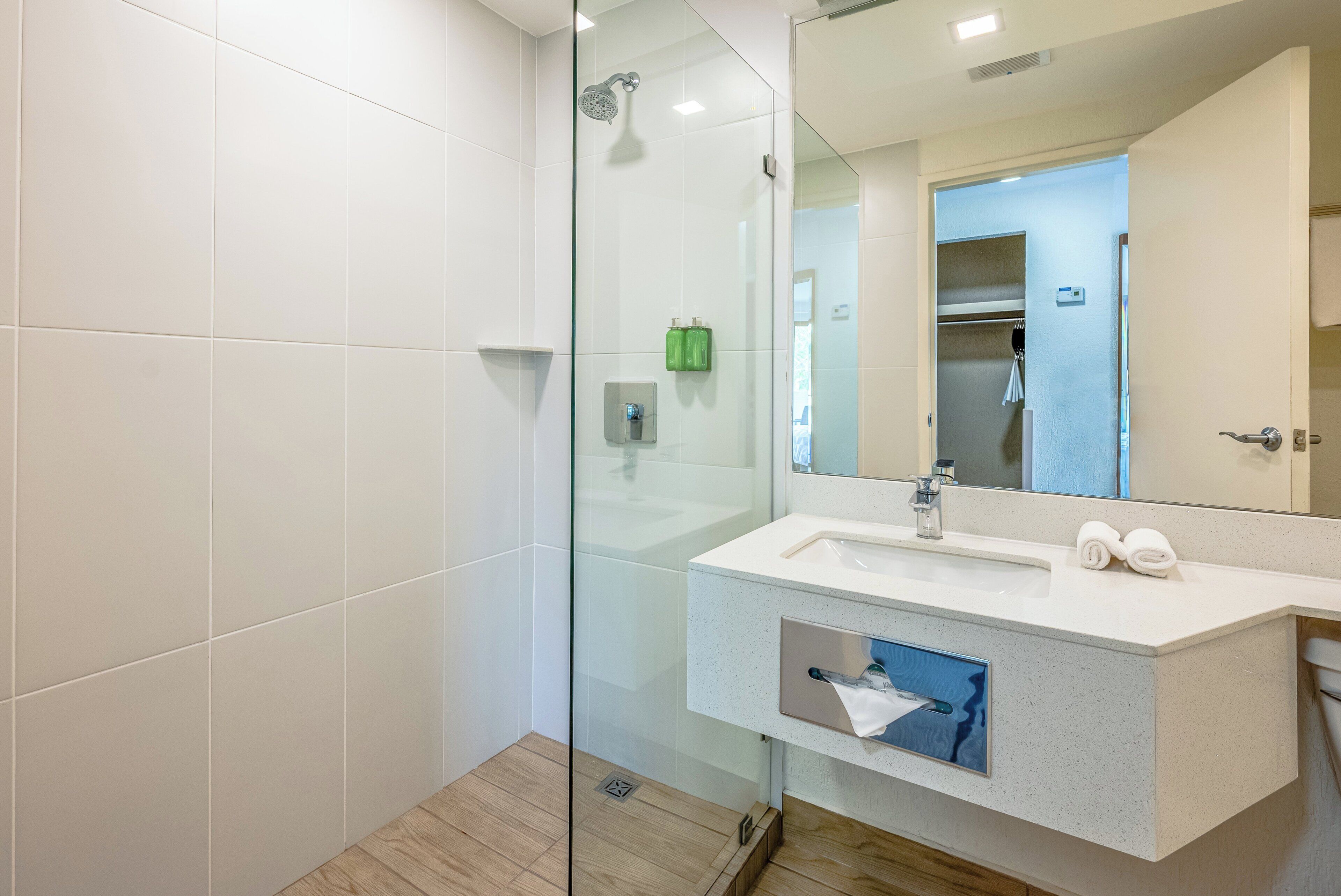 A modern bathroom with a glass shower enclosure, a white sink with a mirror, and a towel rack.