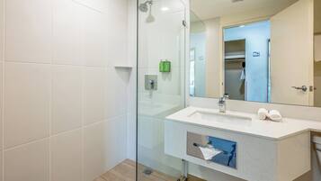 A modern bathroom with a glass shower enclosure, a white sink with a mirror, and a towel rack.