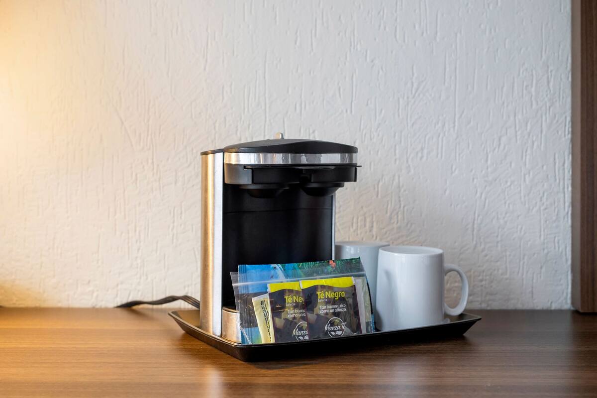 Eine Kaffeemaschine mit einer Tablett voll Kapseln und einer weißen Tasse auf einem Holztisch.
