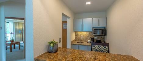 A compact kitchen with granite countertops, a microwave, and a coffee maker.