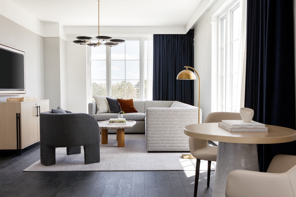 A modern living room with a sofa, armchair, coffee table, and a round table.