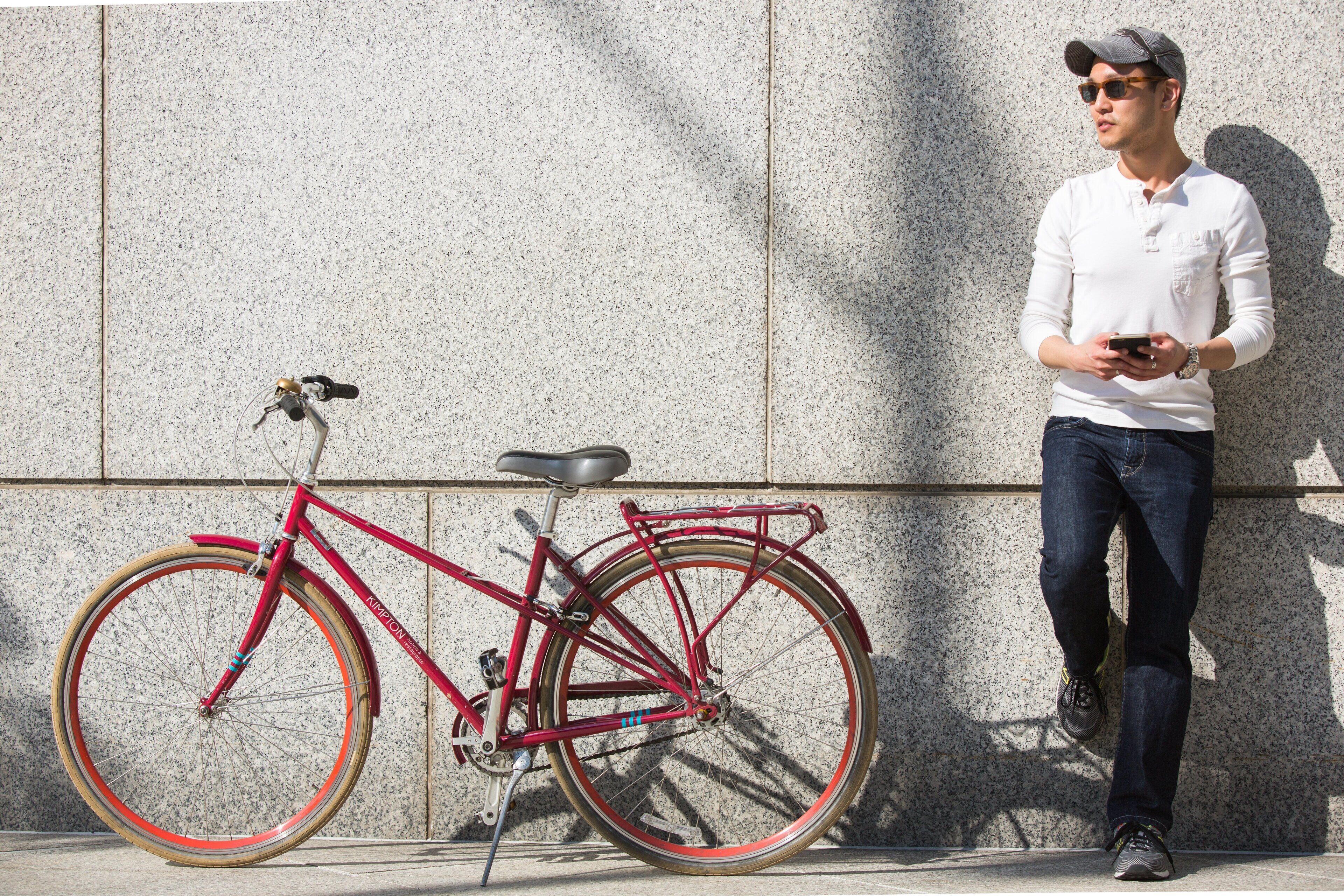 A red bicycle leaning against a textured wall.