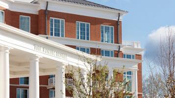 A two-story brick building with a white facade and a balcony. The building has large windows and a sign that reads "The Forum Hotel".