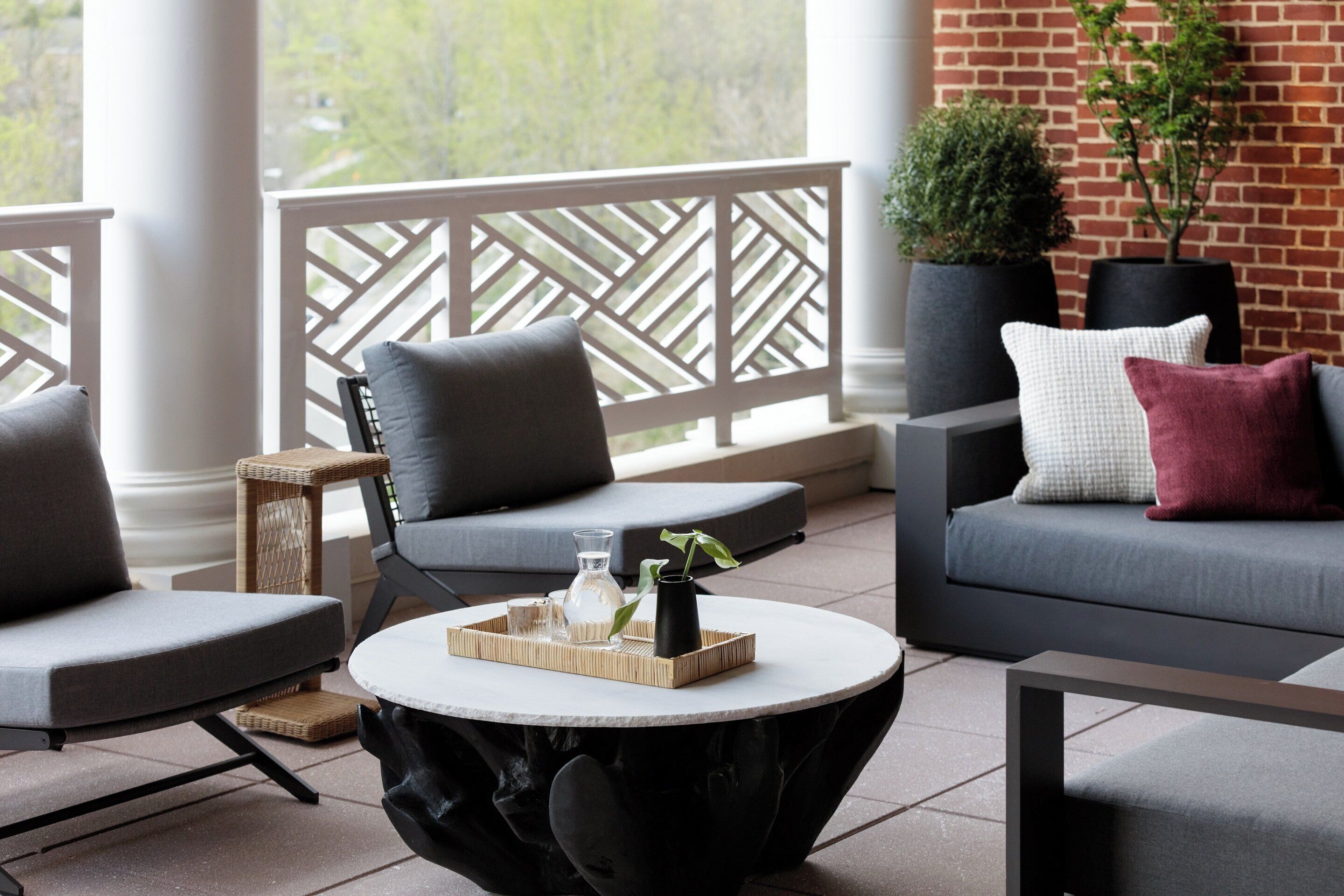 Un espace de détente extérieur moderne, comprenant une table ronde, deux canapés et un arbre à chat.