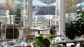 An outdoor dining area with tables set for two, surrounded by large windows offering views of the outdoors. - Kimpton The Forum Hotel by IHG (Charlottesville)