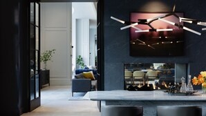 A modern kitchen with a marble countertop, two dark chairs, and a hanging light fixture. - Kimpton The Forum Hotel by IHG (Charlottesville)