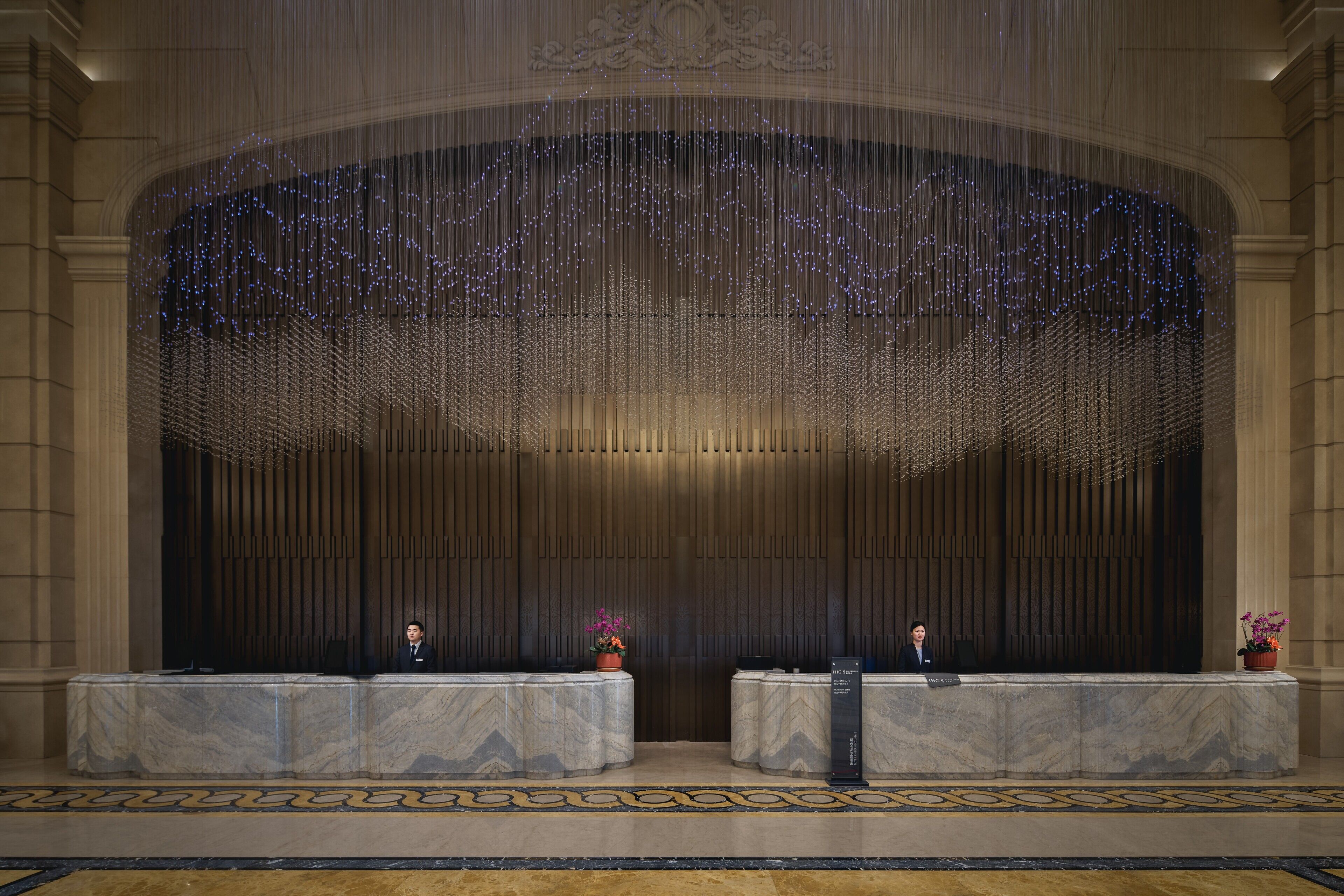 A lobby with marble reception desks, a patterned carpet, and a decorative ceiling.