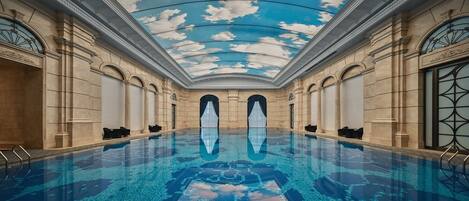 A large indoor swimming pool with a glass ceiling and classical architecture.