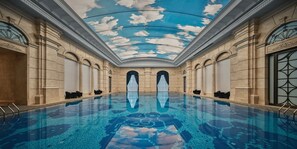 Une vaste piscine intérieure dotée d’un toit en verre et d’une architecture de style classique.