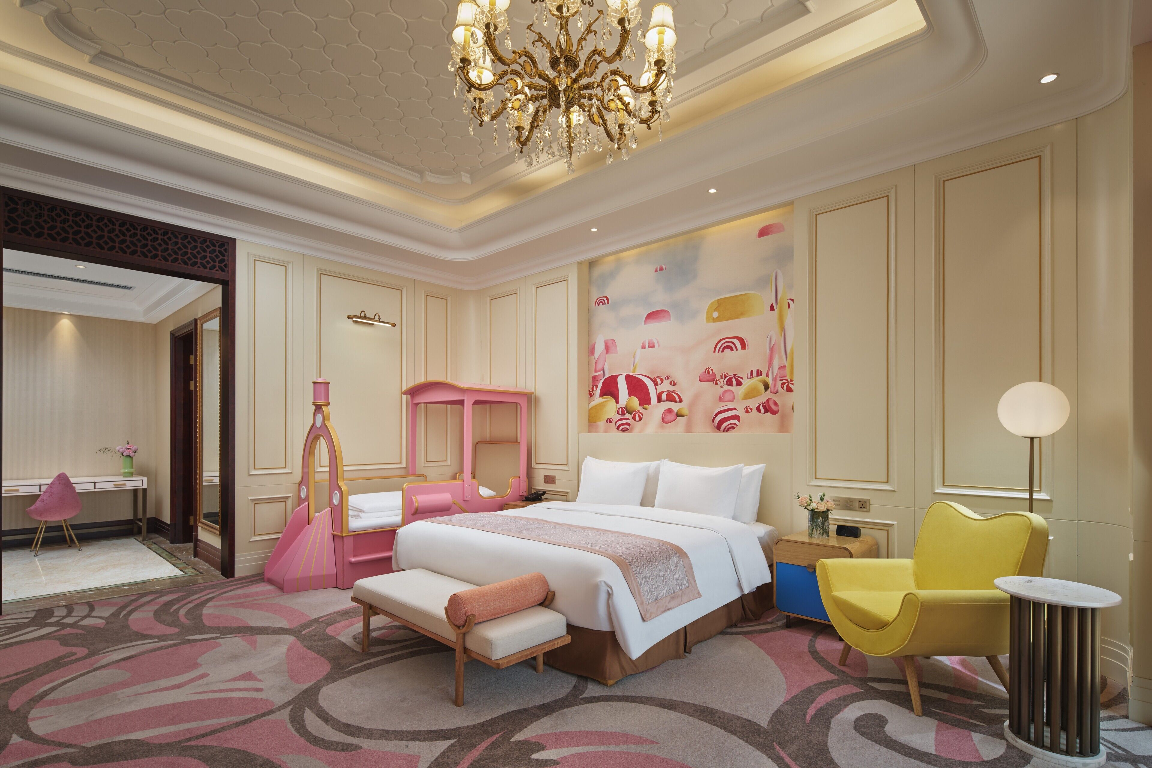 A hotel room with a large bed, a desk, a chair, and a decorative wall.