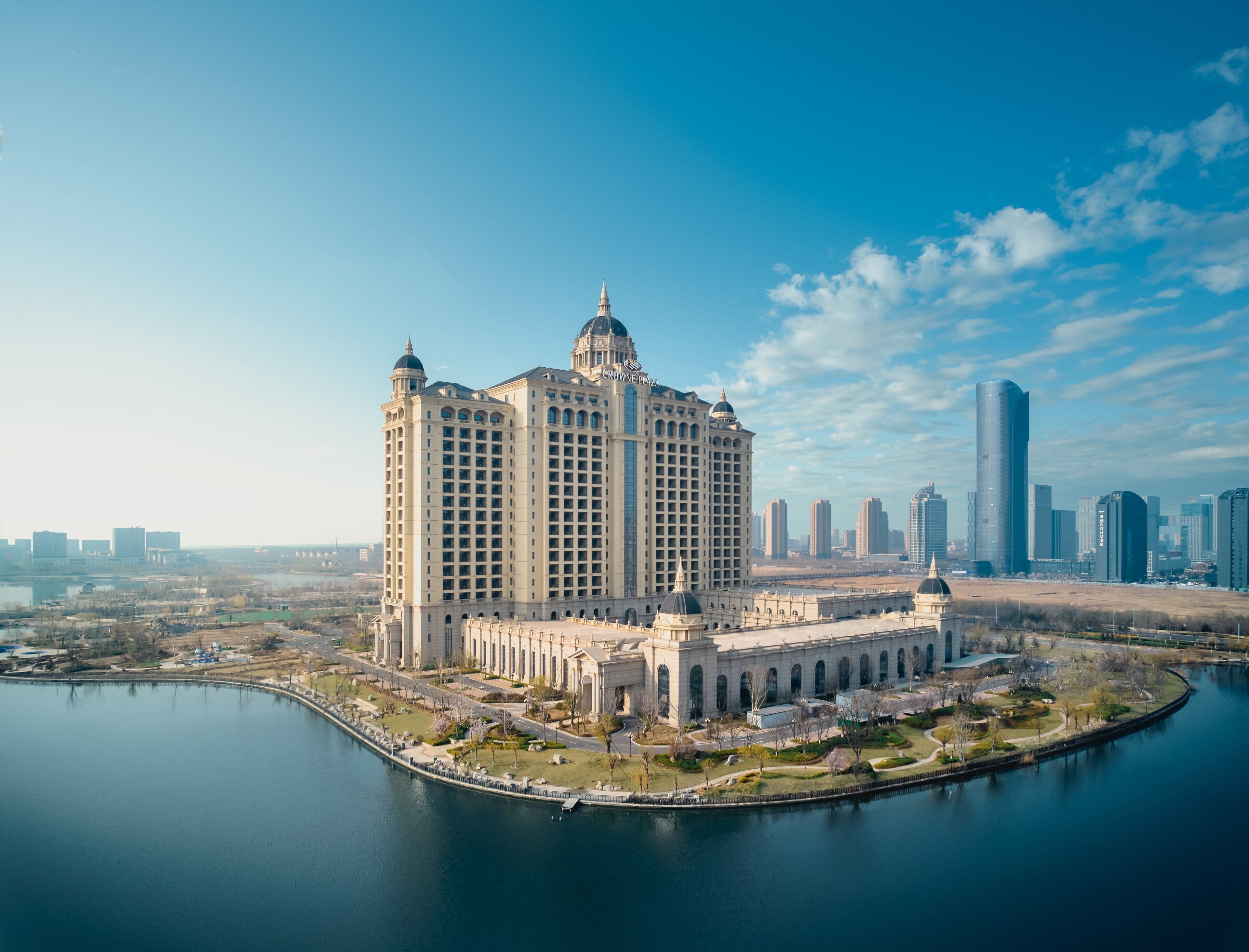 A large, historic hotel with a central courtyard and a body of water in front.