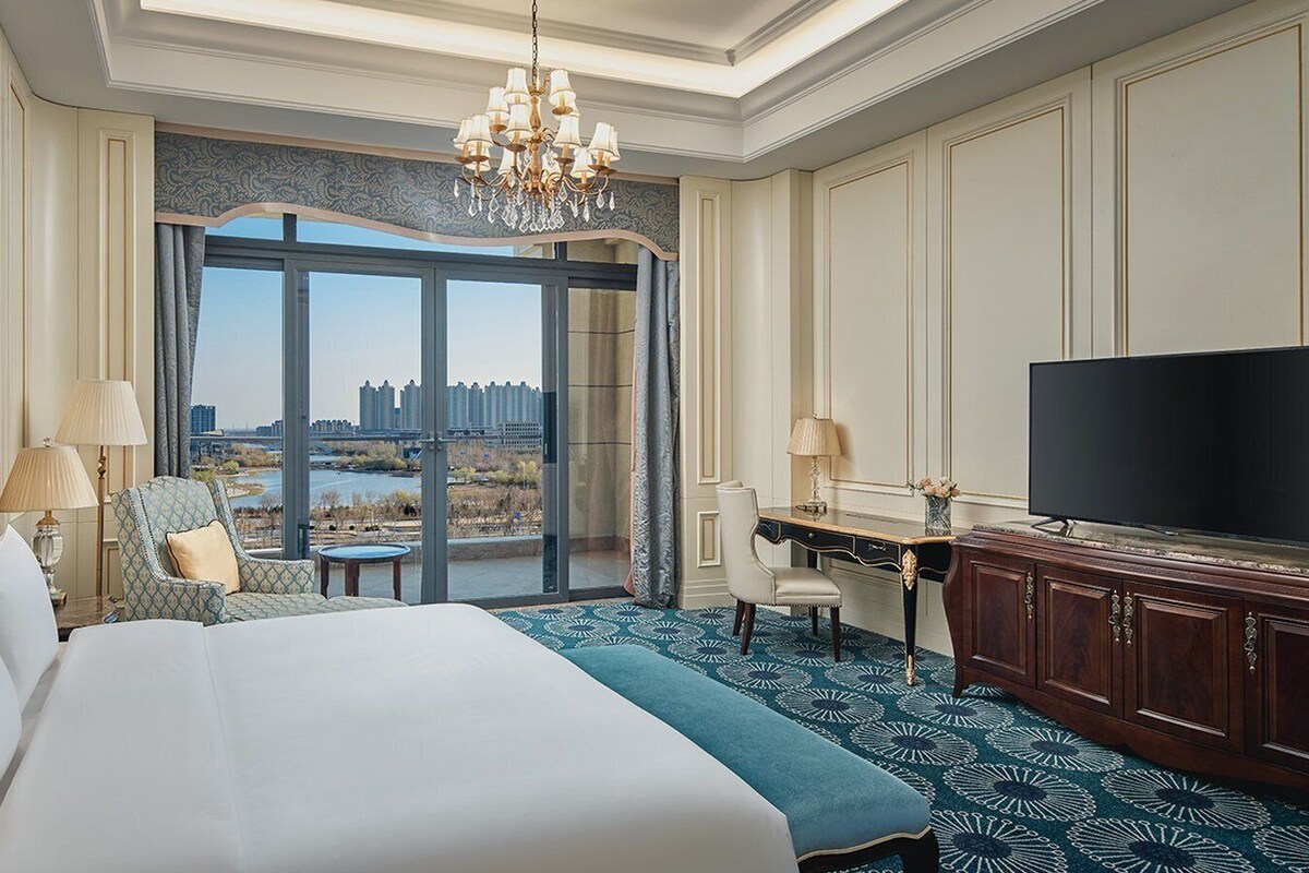 Une chambre d’hôtel avec un grand lit, un bureau, une télévision et une vue sur le paysage urbain.